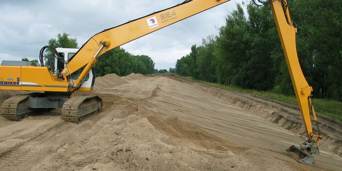 Bild: Deichbauarbeiten - Ein Bagger ebnet den Sand am Deichhügel.
