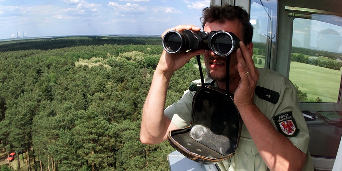 Bild: Alf Pommerinke schaut durch sein Fernglas, um den Wald von einem speziellen hochrangigen Feuerwachturm