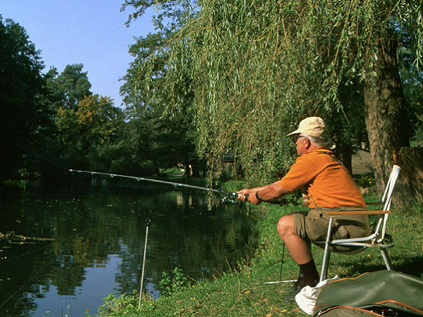 Ein Angler hat seine Angel ausgeworfen und wartet auf einen Fang.